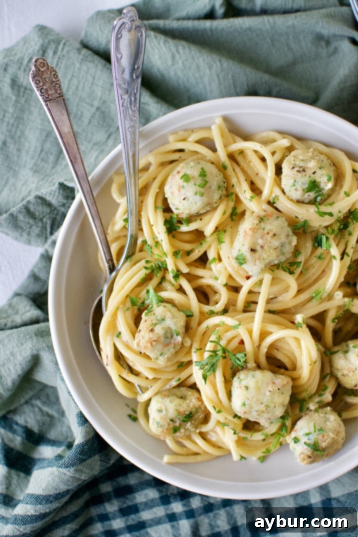 Beautifully plated Italian Shrimp Balls served over cooked bucatini pasta in a white bowl, ready to enjoy.
