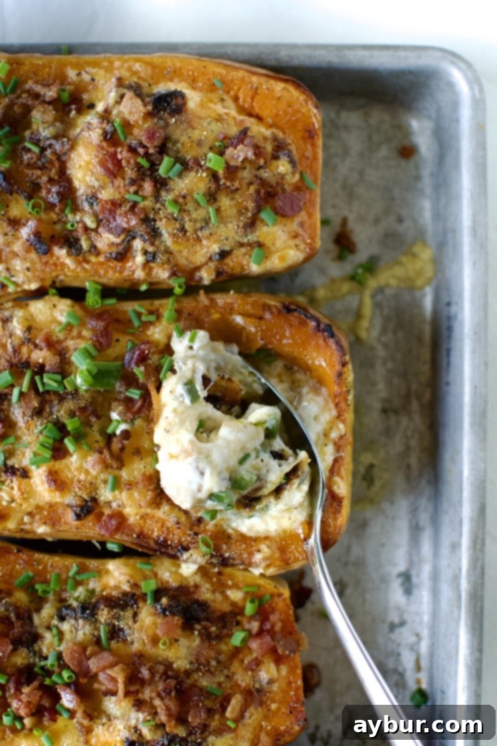 Jalapeño Popper Butternut Squash Boats 2 Cooked Stuffed Butternut Squash, half-eaten with a spoon, showing the creamy filling and golden-brown top.