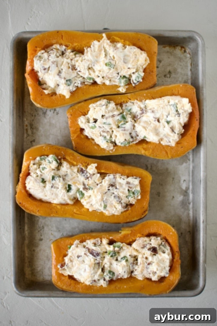 Jalapeño Popper Butternut Squash Boats 7 A spoon adding the creamy jalapeño popper stuffing into a scooped-out butternut squash half.