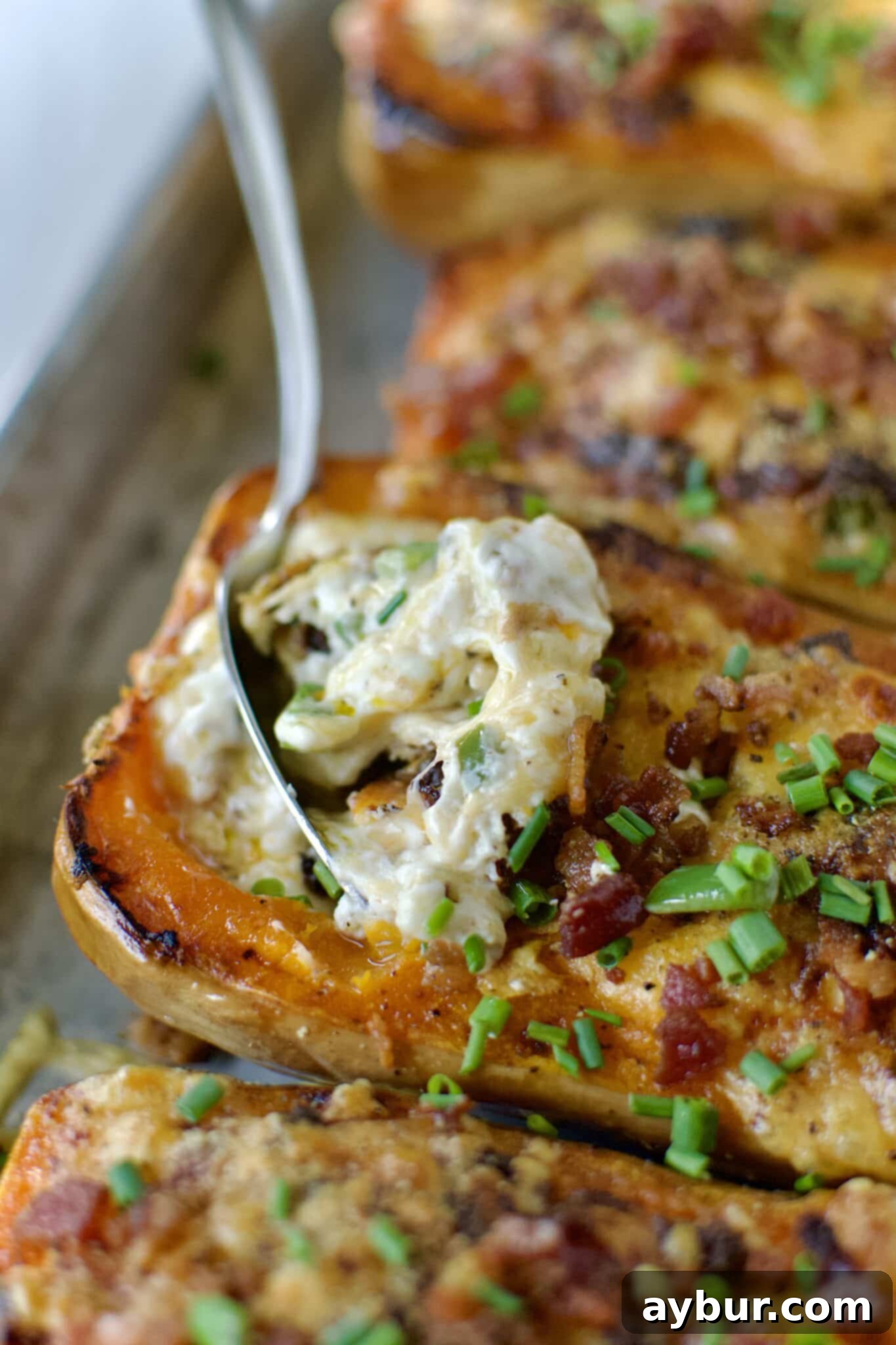 Jalapeño Popper Butternut Squash Boats 10 A close-up shot of a Stuffed Butternut Squash with a spoon taking a scoop, highlighting the creamy, cheesy filling.