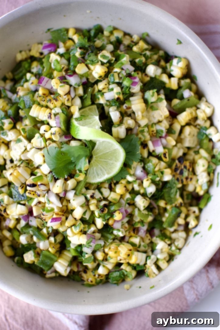 Smoky Sweet Corn and Pepper Salsa 9 Close-up of freshly prepared Roasted Chili-Corn Salsa in a rustic bowl, vibrant colors of corn, peppers, and cilantro clearly visible, garnished with a lime slice and cilantro.