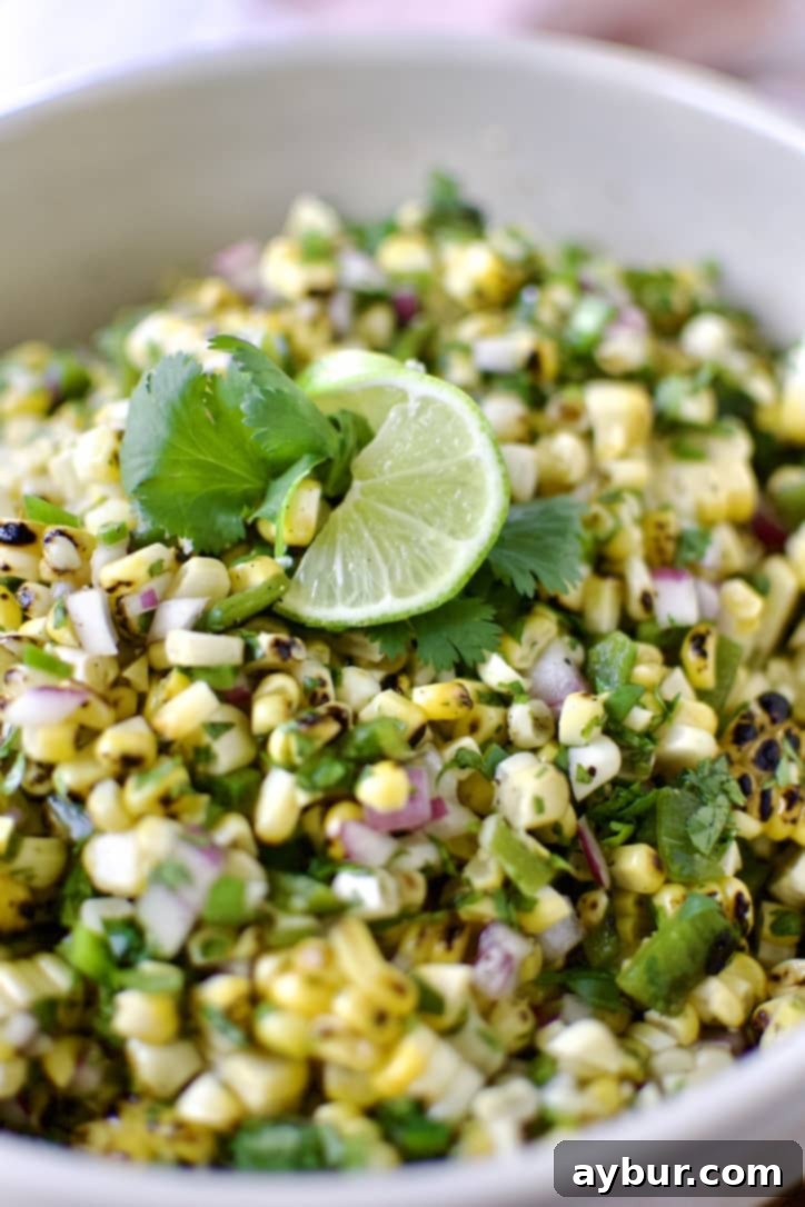 Smoky Sweet Corn and Pepper Salsa 10 Close-up of a serving of Roasted Chili-Corn Salsa, beautifully presented with a lime wedge and fresh cilantro, highlighting the vibrant colors and textures of the ingredients.