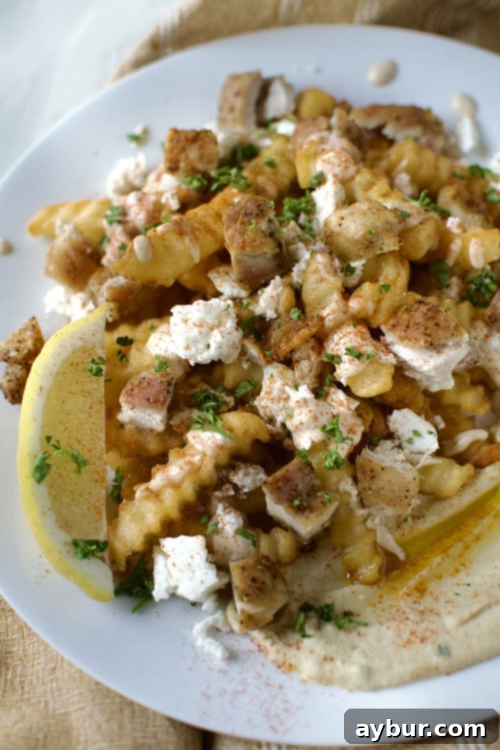 Loaded Greek Chicken Fries 13 Greek Fries assembled nacho style on a white plate, ready to eat.