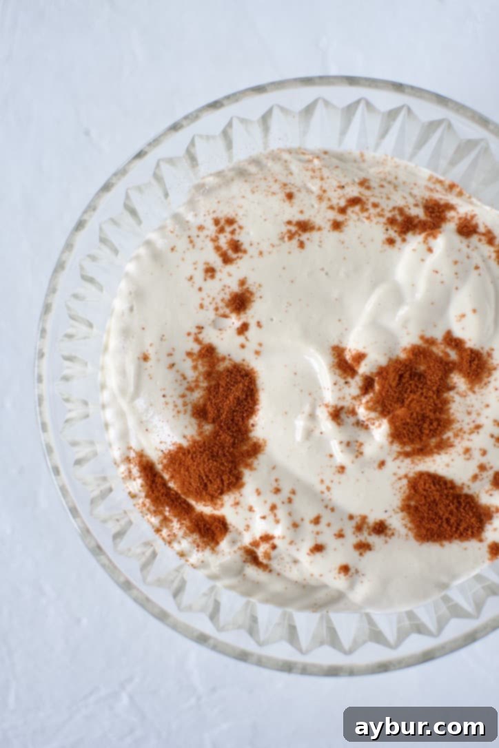 Loaded Greek Chicken Fries 4 Garlic Sauce in a bowl topped with Paprika.