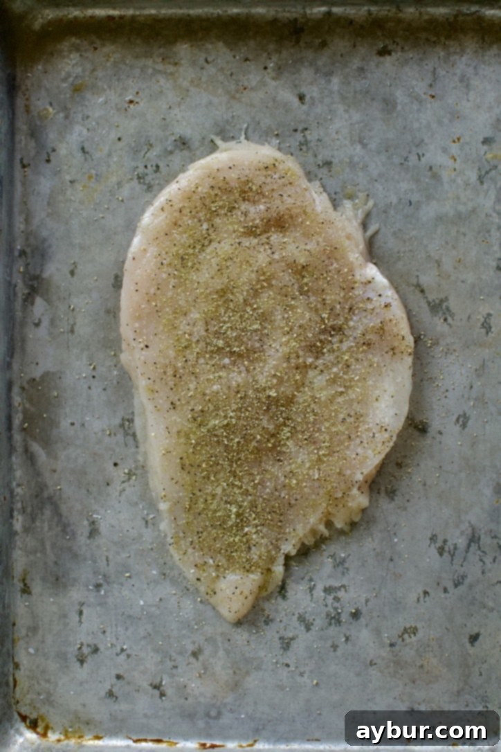 Mediterranean Lemon Orzo Chicken 5 Chicken breast on a sheet pan seasoned with salt, pepper, and greek seasoning.