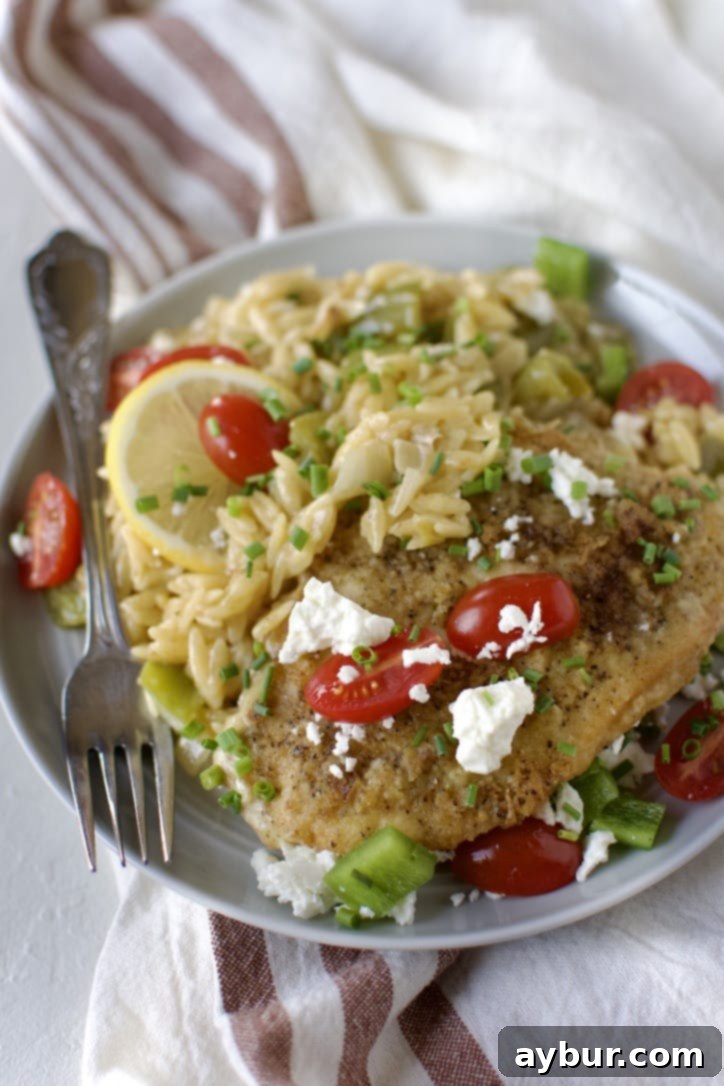 Mediterranean Lemon Orzo Chicken 9 Lemon Orzo Chicken with Feta and Tomatoes finished and ready to eat, on a plate.
