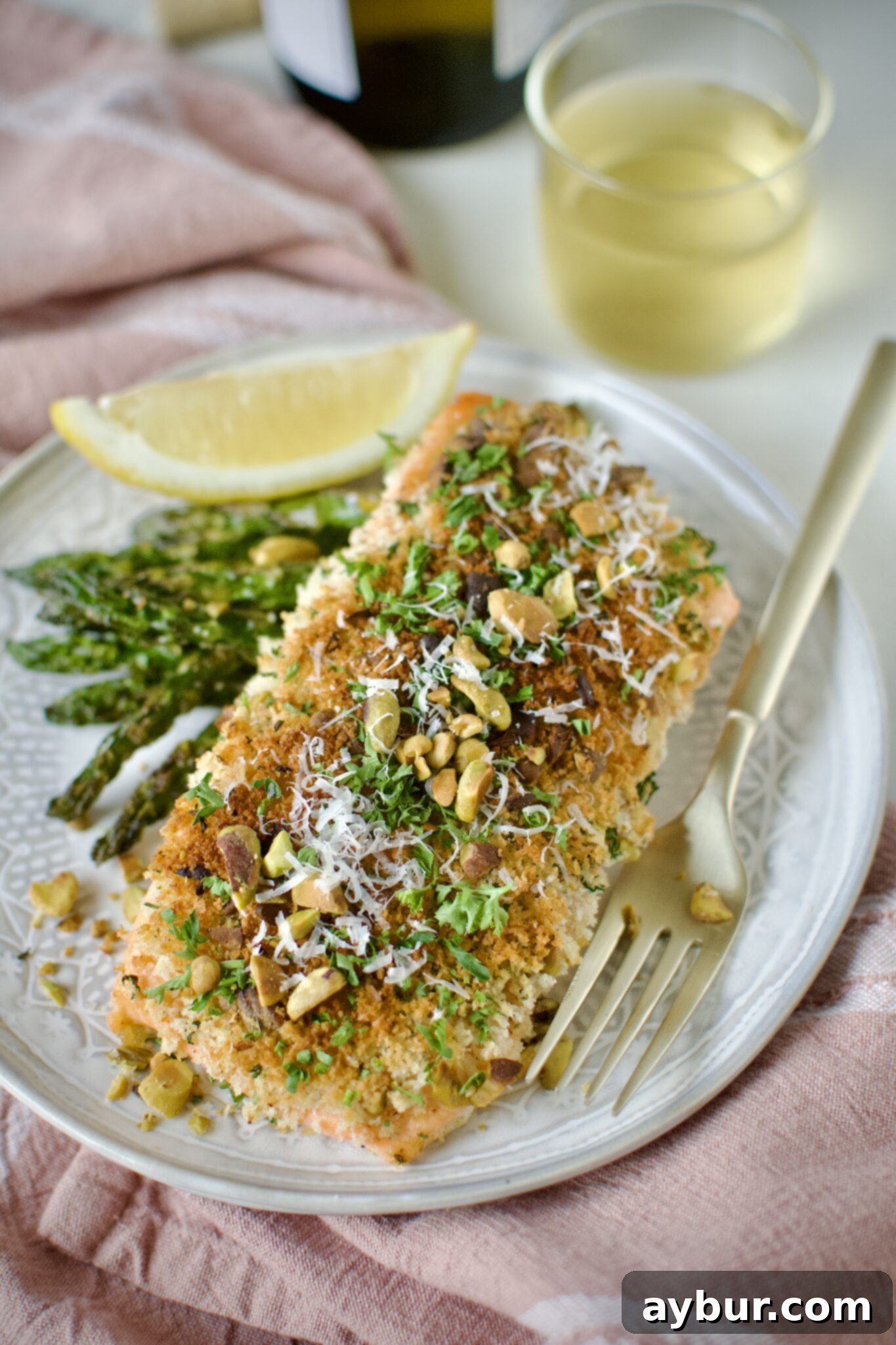 Crisp Pistachio Salmon 8 Pistachio Crusted Salmon on a plate with some grilled asparagus and a lemon wedge. Ready to eat.