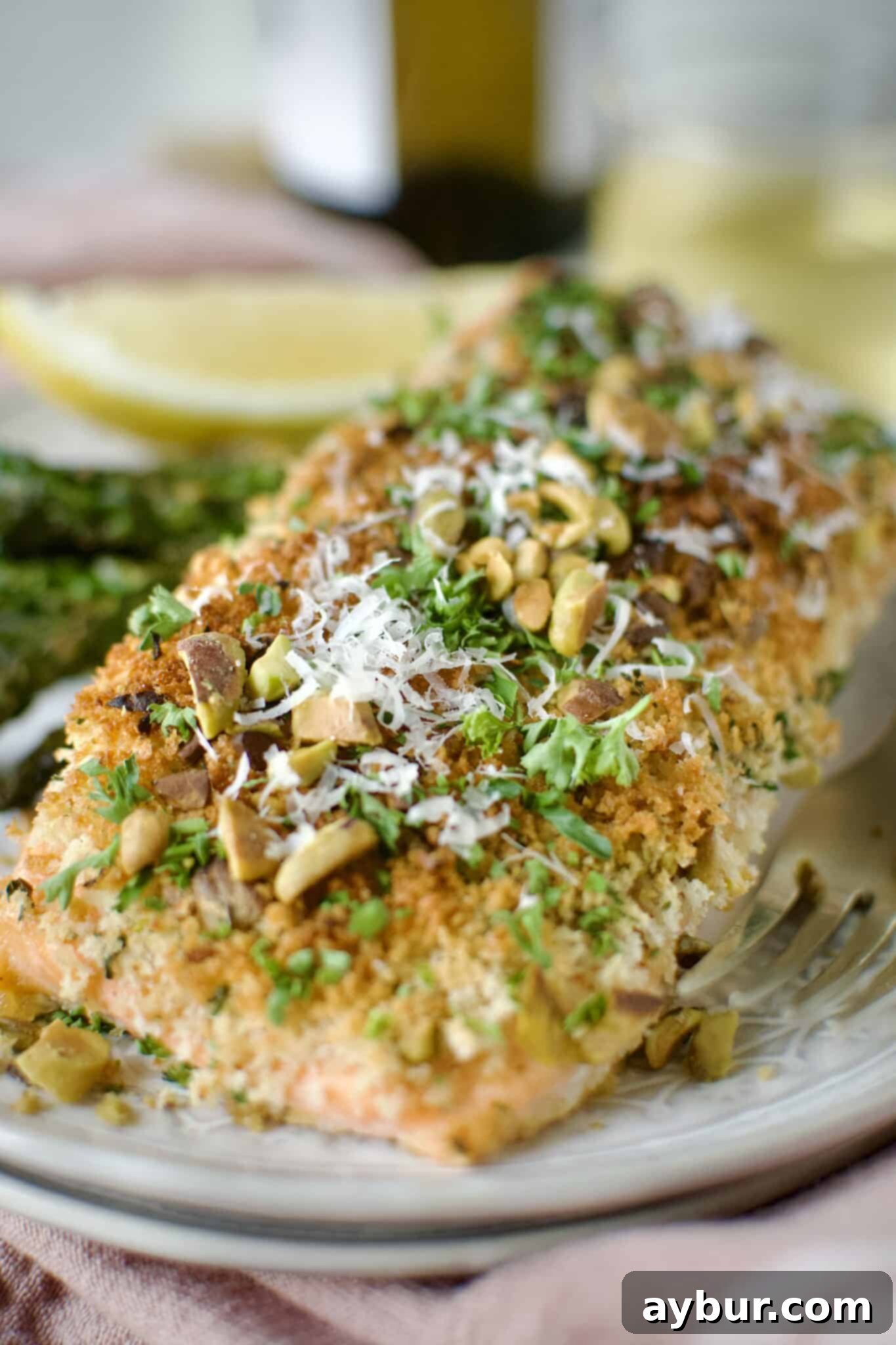 Crisp Pistachio Salmon 9 Pistachio Crusted Salmon on a plate with some grilled asparagus and a lemon wedge. Ready to eat.