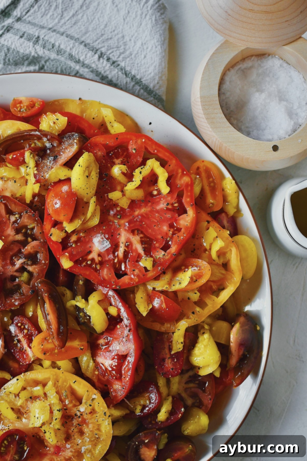 Creamy Burrata and Zesty Banana Pepper Tomato Salad 2 Tomato salad being topped with flakey sea salt and olive oil.