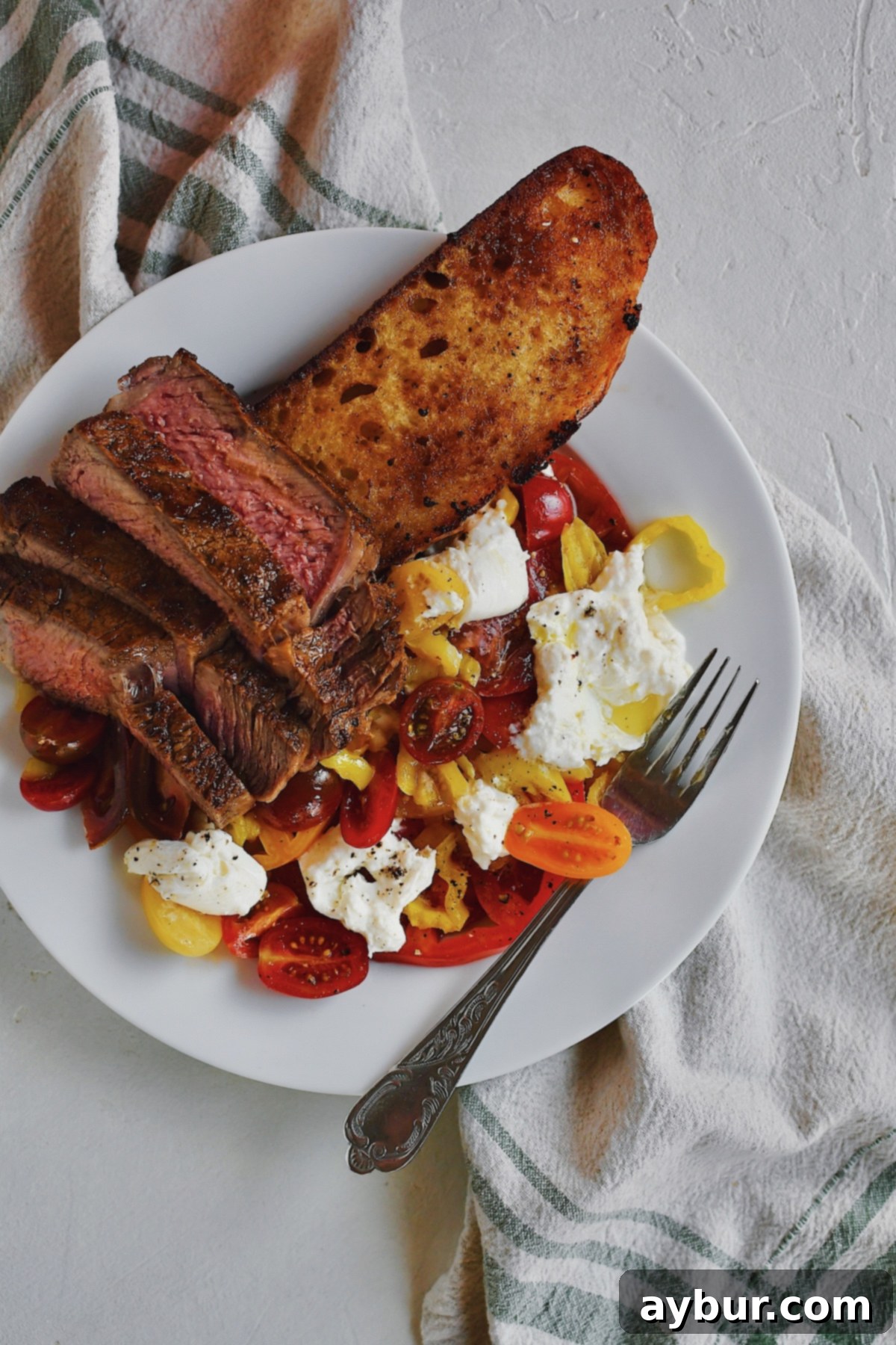 Creamy Burrata and Zesty Banana Pepper Tomato Salad 8 Tomato Salad optionally topped with burrata cheese and served with a grilled steak and slice of sourdough bread.
