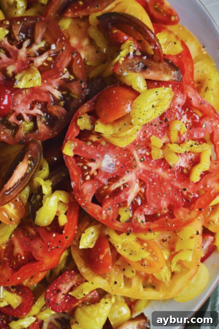 Creamy Burrata and Zesty Banana Pepper Tomato Salad 10 Close up of a seasoned tomato salad, a large flake of sea salt can be seen.