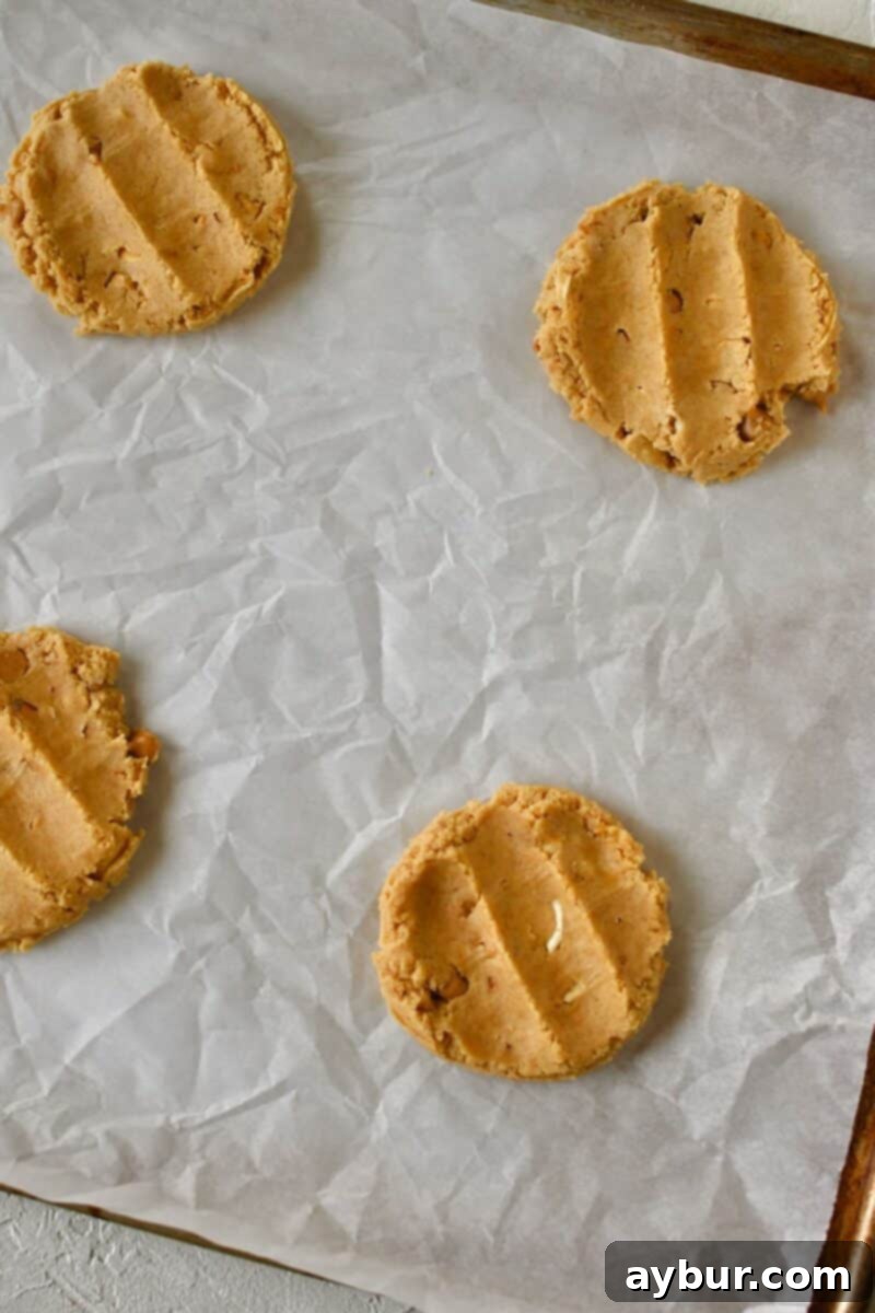Flattened cookie dough disks on a baking sheet, creating a cavity perfectly ready for the marshmallow cream filling.