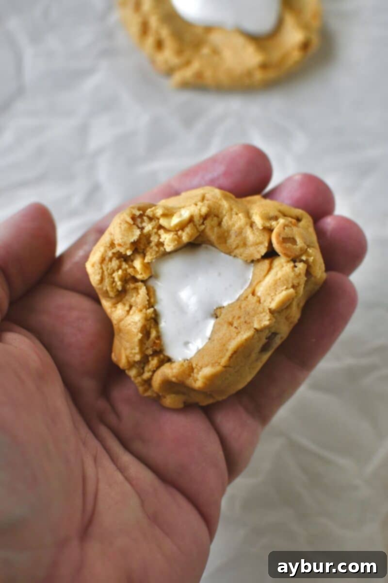The process of gently folding the cookie dough edges over the marshmallow cream to encase the filling.