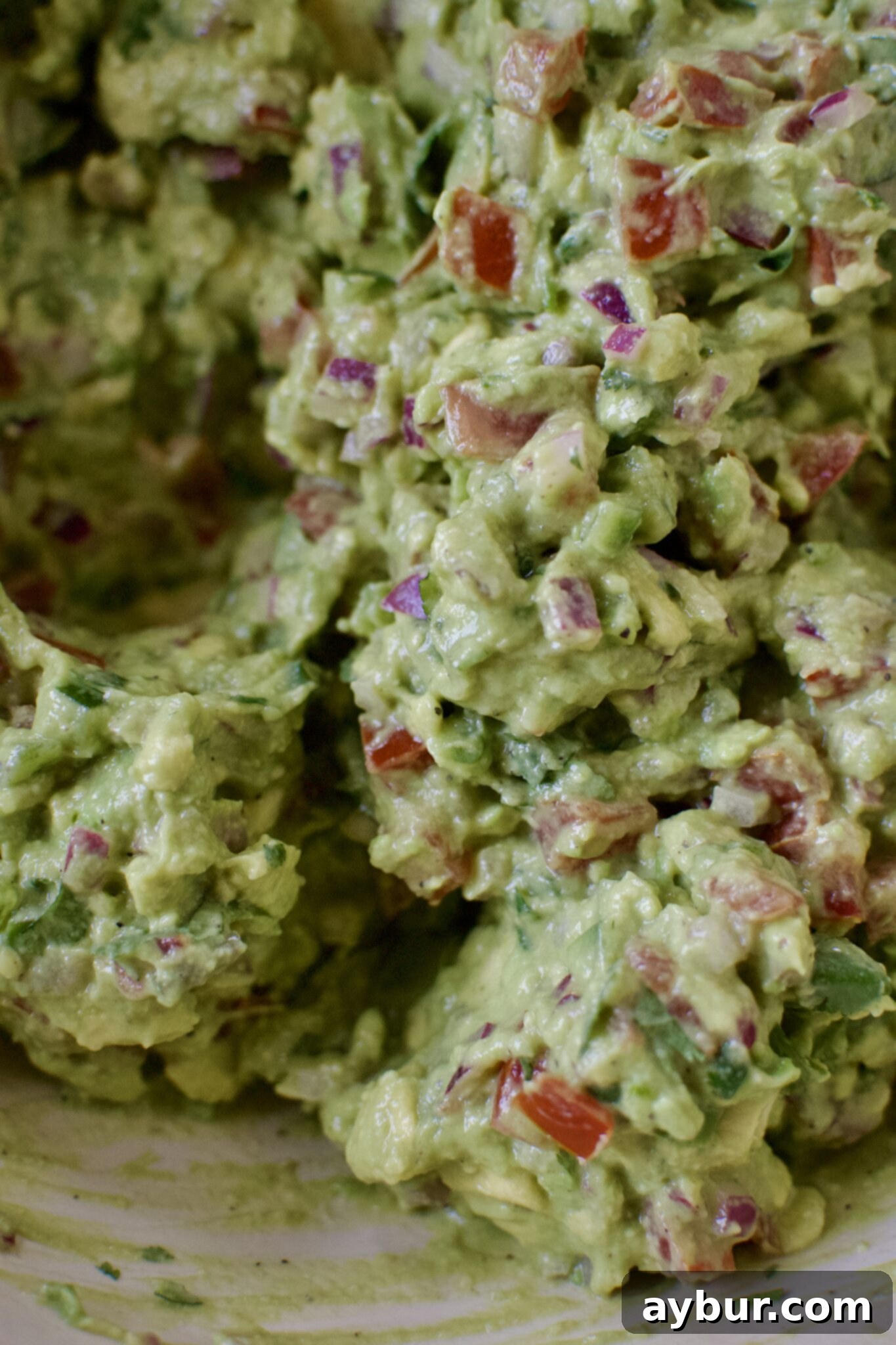 Freshly smashed and mixed guacamole in a large bowl, garnished with cilantro.