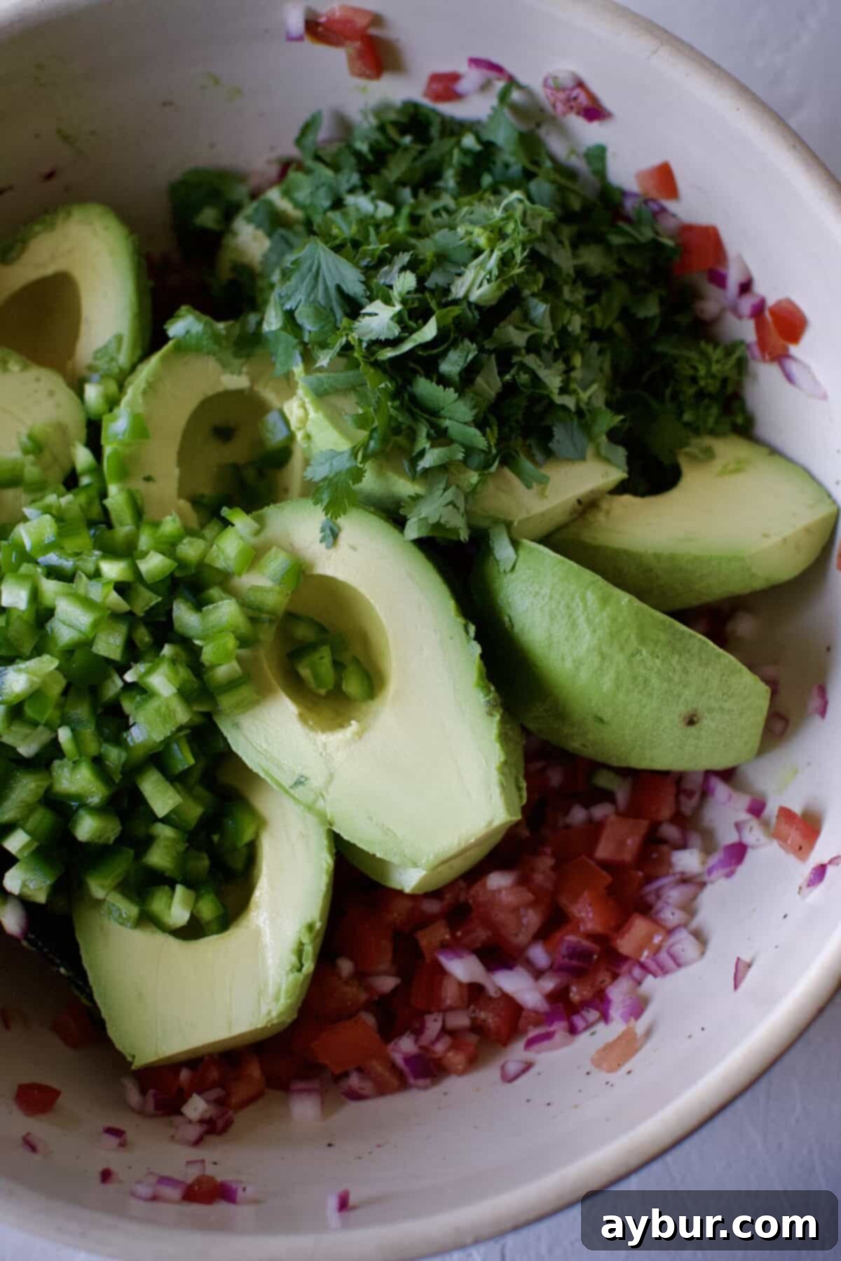 Avocado, diced jalapeño, and minced cilantro added to the bowl with the prepared onion, tomatoes, and lime juice mixture.