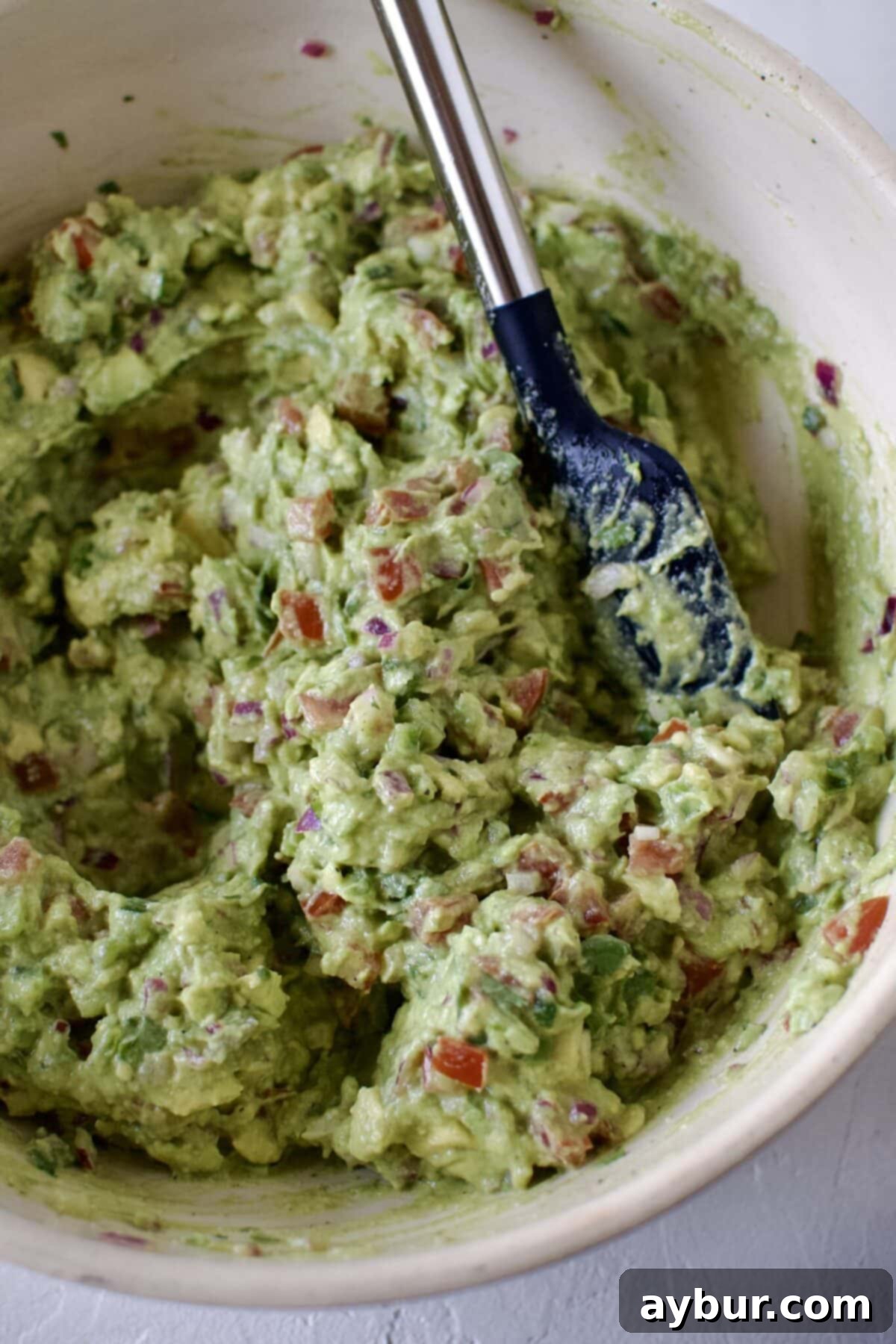 Freshly smashed and mixed guacamole in a large serving bowl, ready to be enjoyed.
