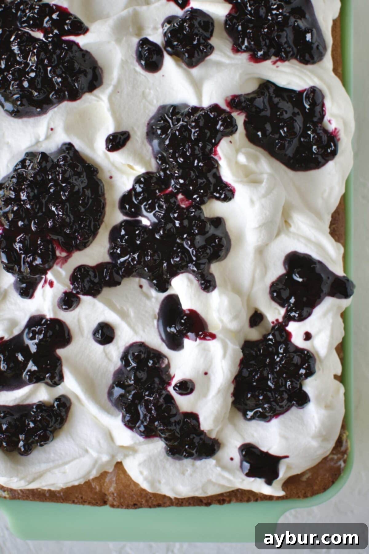 Effortless Tres Leches Cake 13 Carefully dropping dollops of sweet blueberry jam onto the whipped cream layer of the Tres Leches cake.