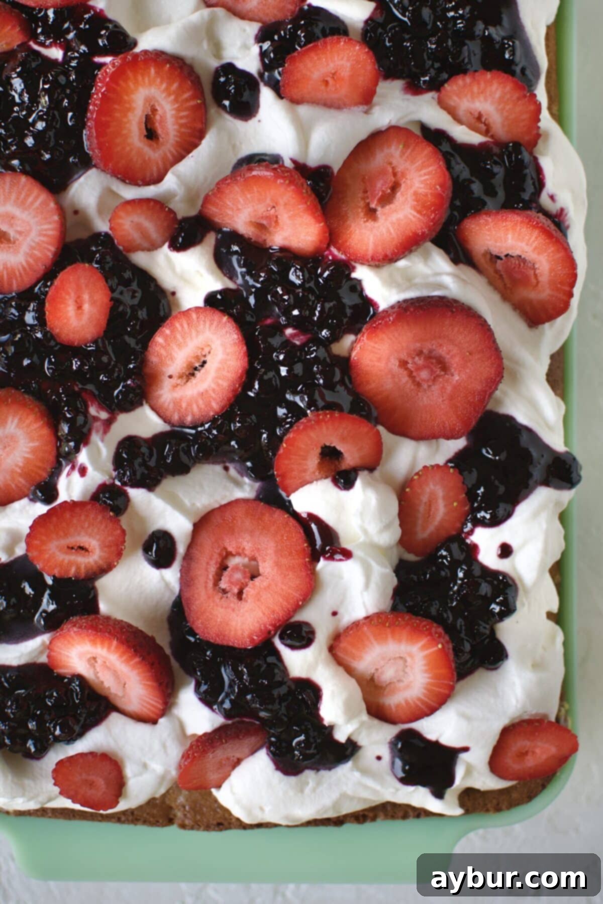 Effortless Tres Leches Cake 14 Arranging fresh, thinly sliced strawberries artfully on top of the Tres Leches cake with blueberry jam.