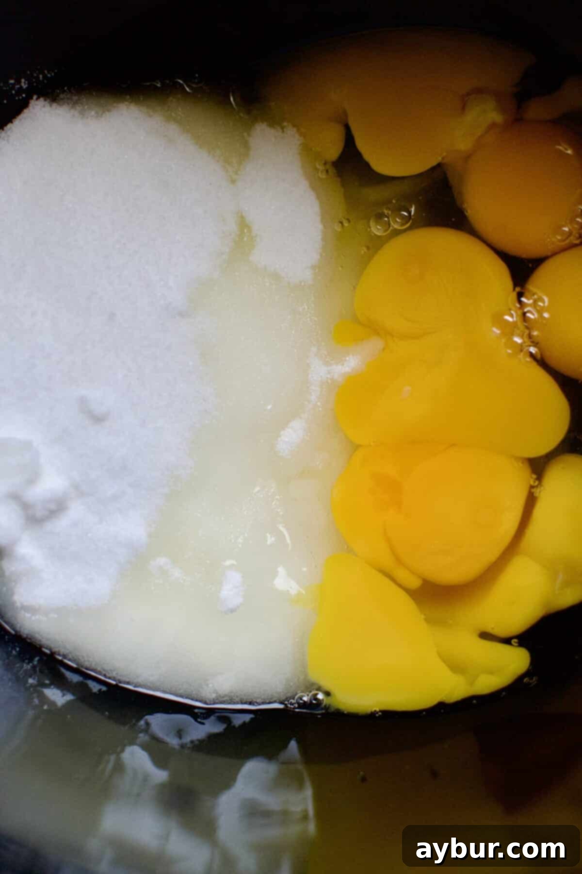 Effortless Tres Leches Cake 4 Eggs and sugar in a stand mixer bowl, before whipping, showing the initial state of ingredients.