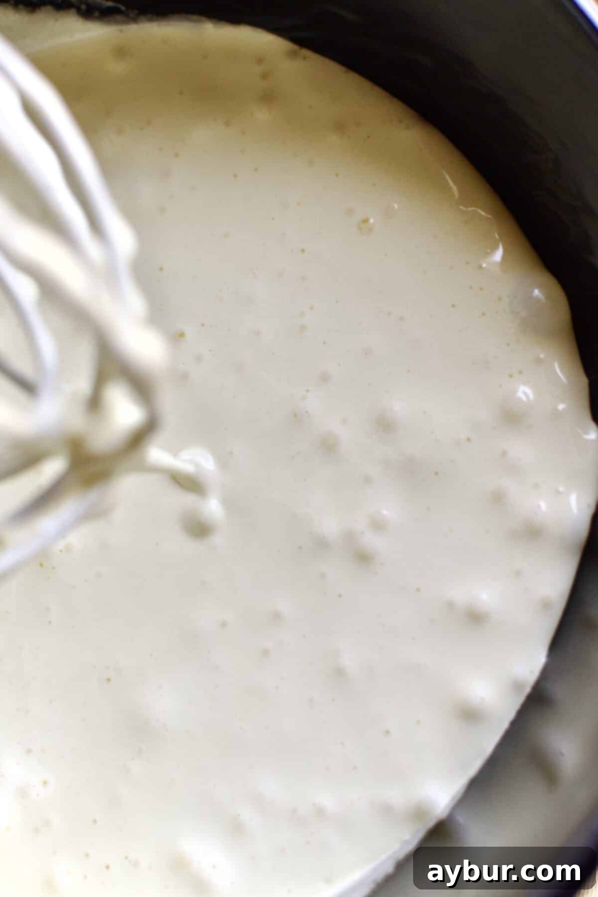 Effortless Tres Leches Cake 5 Perfectly whipped eggs and sugar in a stand mixer bowl, showing light, fluffy, and voluminous texture.