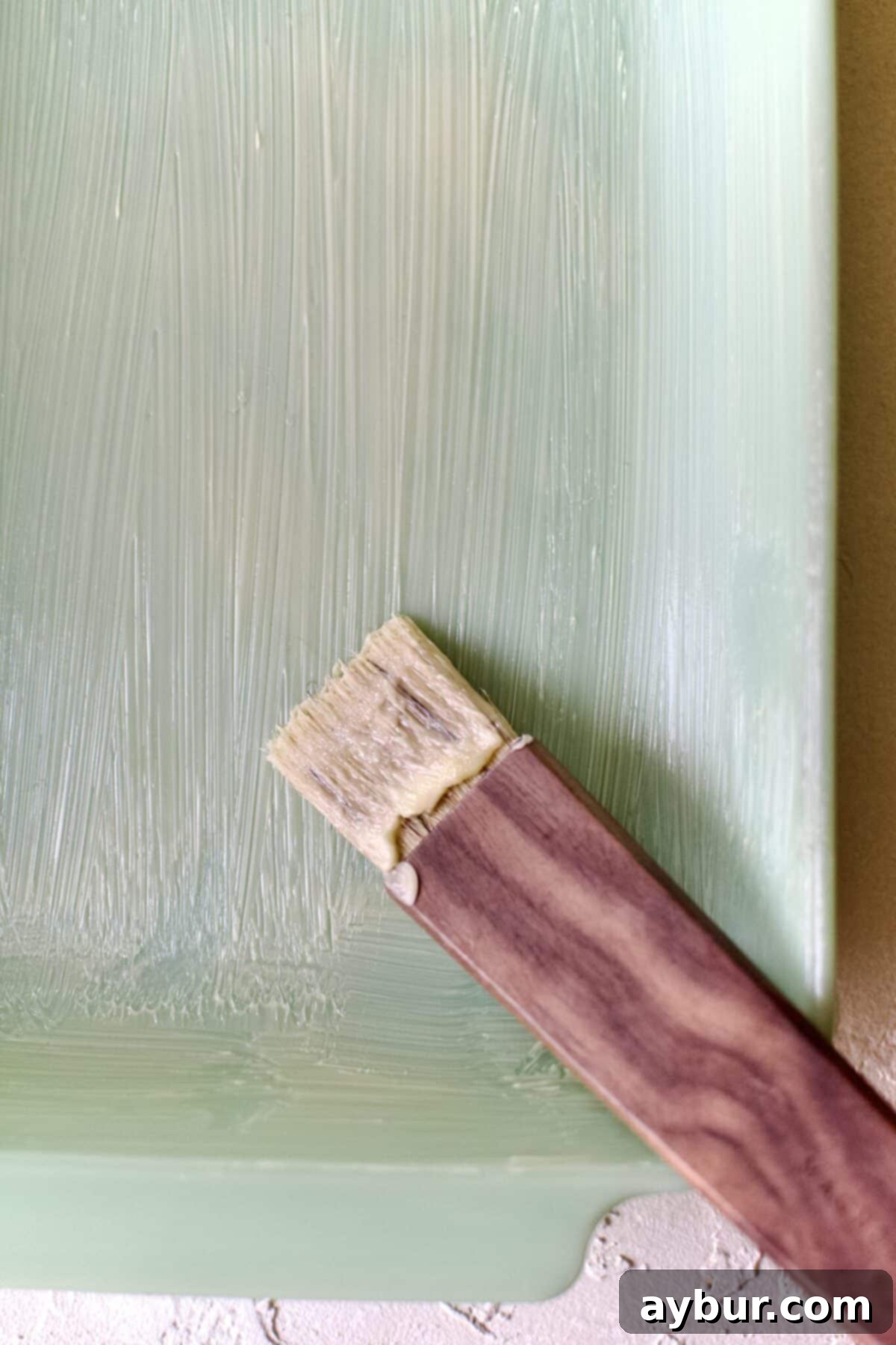 Effortless Tres Leches Cake 6 Applying butter evenly to a baking dish using a brush, preparing it for the Tres Leches cake batter.