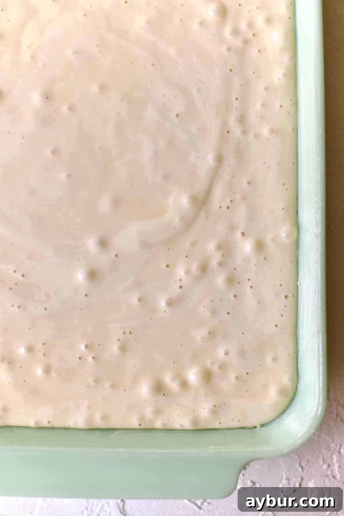 Effortless Tres Leches Cake 7 Smooth Tres Leches cake batter evenly spread in a buttered baking dish, ready for baking.