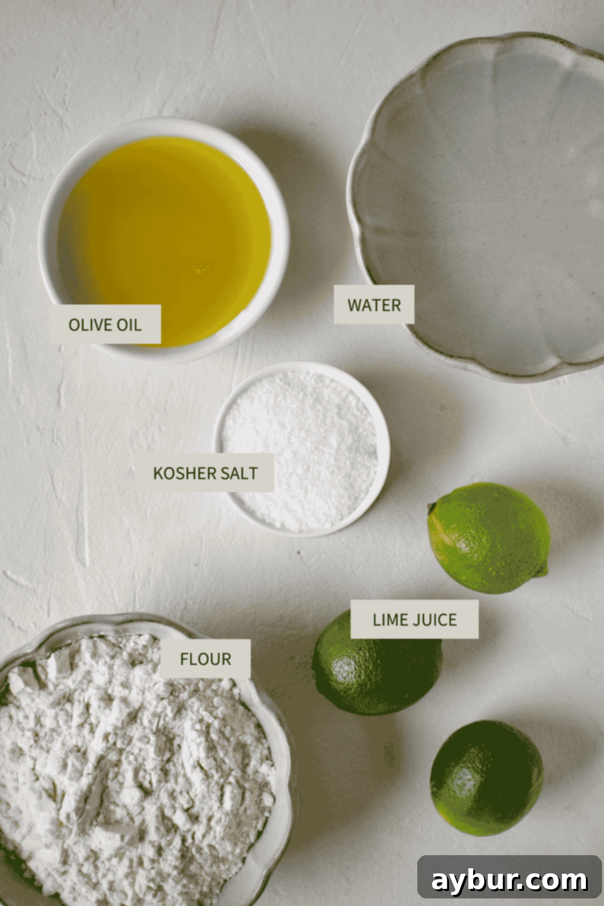 Simple ingredients laid out for homemade flour tortillas: all-purpose flour, kosher salt, water, fresh lime juice, and olive oil.