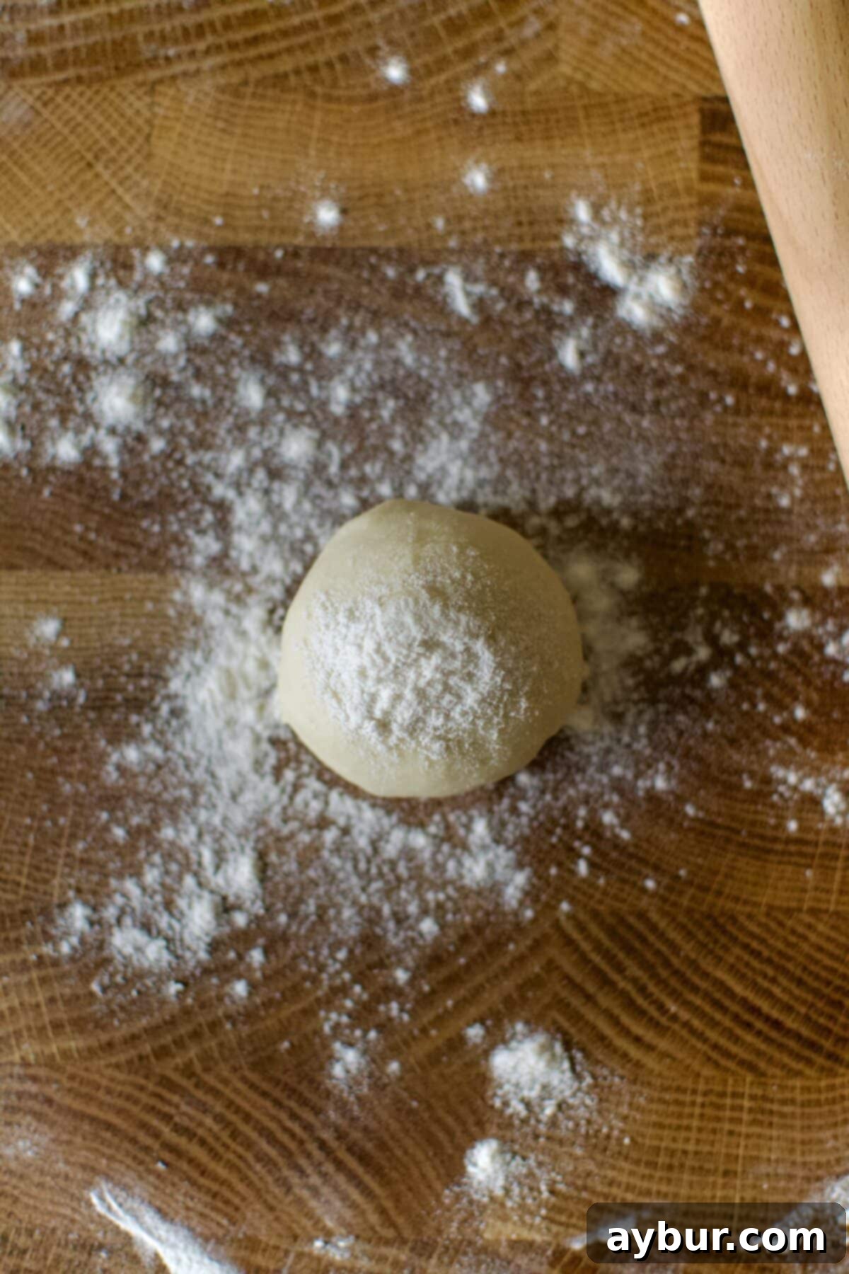 A ball of tortilla dough lightly dusted with flour, perfectly prepared and centered for rolling out.