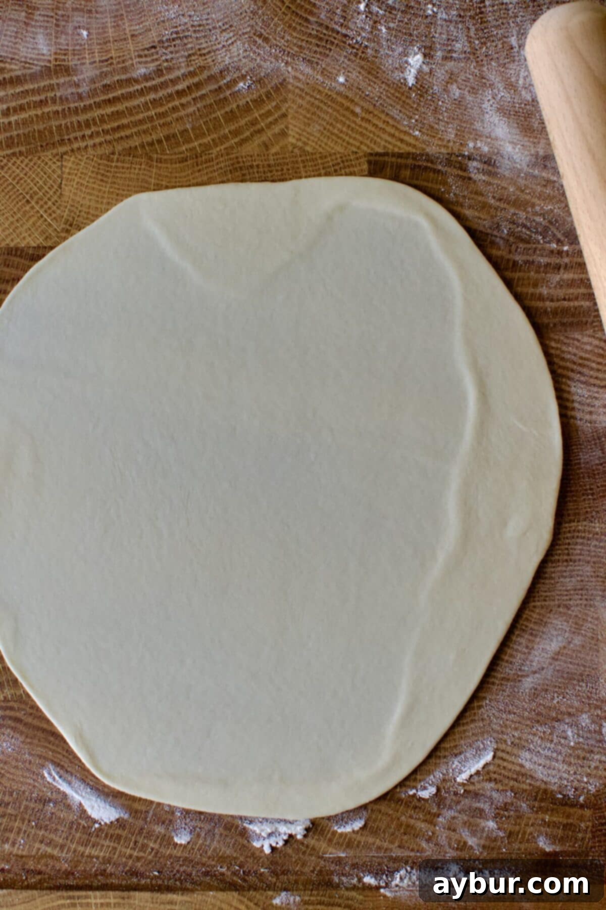 A perfectly rolled, thin, round homemade flour tortilla ready for cooking on the griddle.
