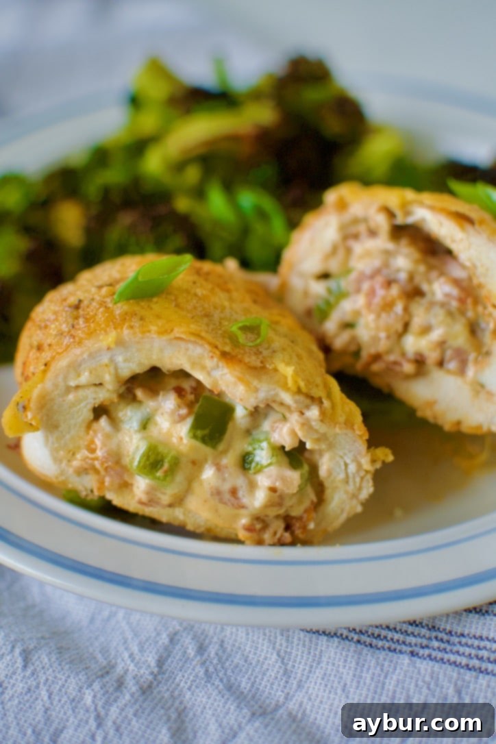Jalapeño Popper Stuffed Chicken 15 Stuffed Chicken Breast with Cheese cut open on a plate with roasted broccoli ready to eat.