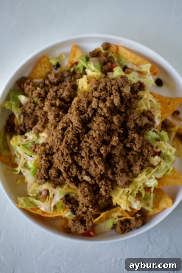 A generous sprinkling of shredded cheddar cheese over the ground beef layer.