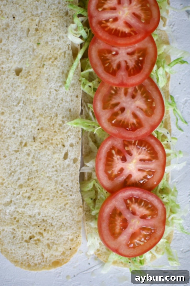 Adding fresh tomato slices to the Italian Sub.