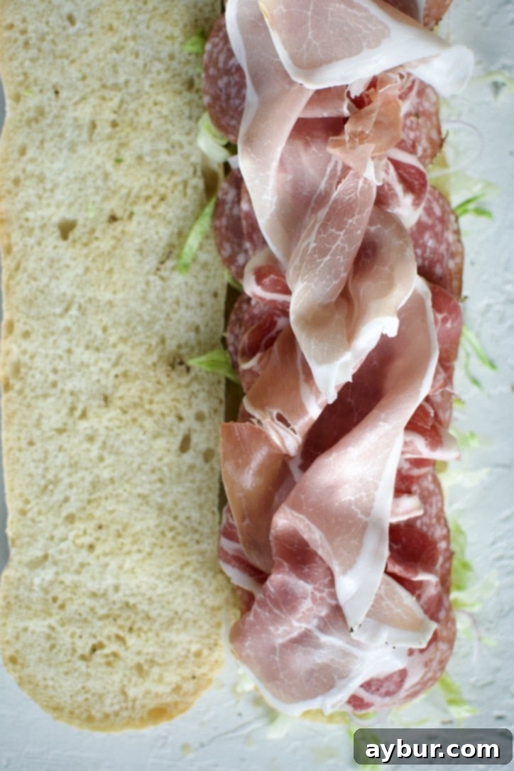 Arranging various salamis and cured meats on the Italian Sub.