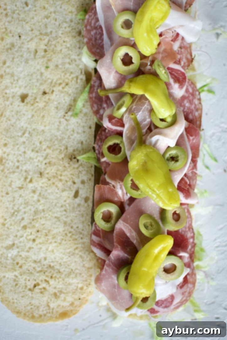 Adding sliced olives and vibrant pepperoncini peppers to the Italian Sub.