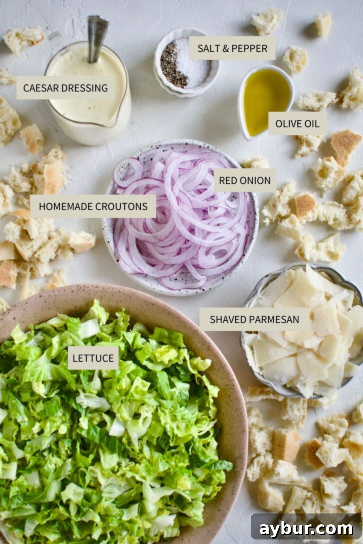 Traditional Caesar Salad 3 A collection of fresh ingredients laid out on a wooden board, including crisp romaine lettuce, a red onion, a block of Parmesan cheese, and a bowl of creamy Caesar dressing, all necessary for making the Classic Caesar Salad.