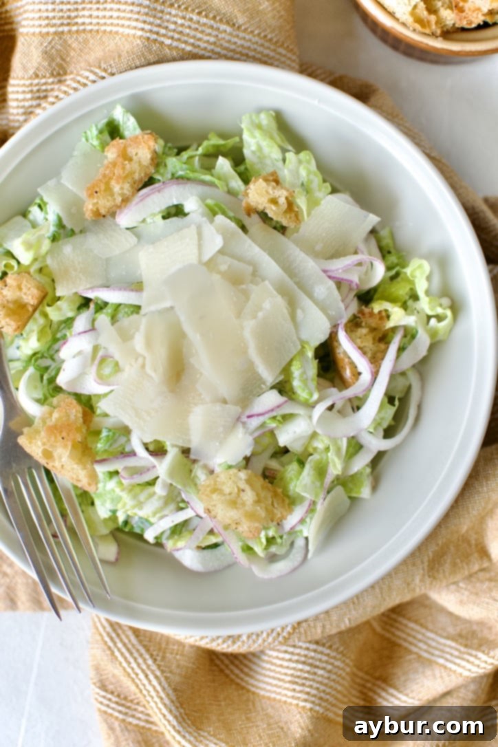 Traditional Caesar Salad 8 A close-up of a serving of Classic Caesar Salad in a bowl, showcasing the dressing-coated romaine, homemade croutons, and delicate shaved Parmesan on top.