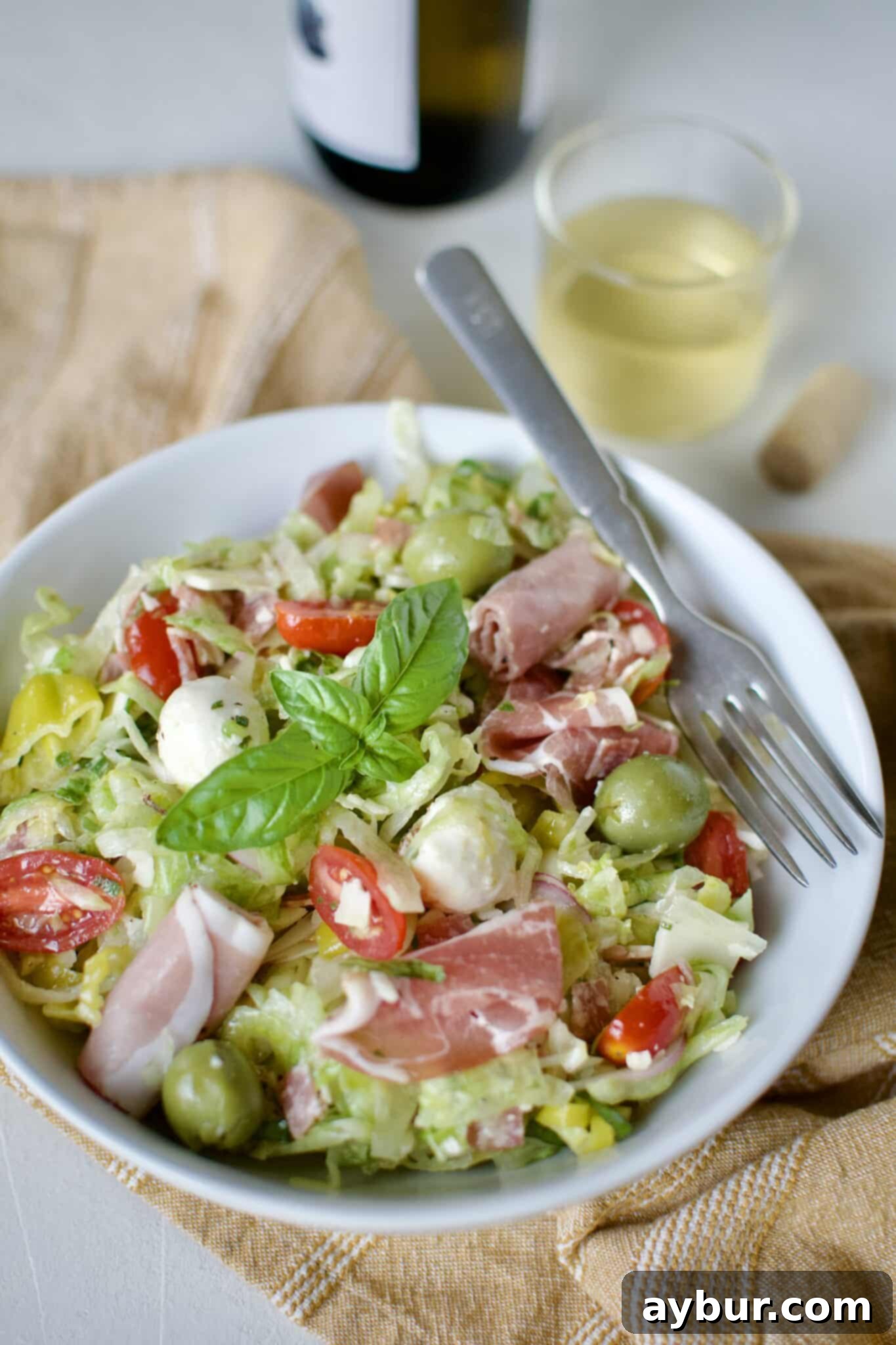 a single serving of Italian Chopped Salad in a small bowl with a glass of white wine behind it.