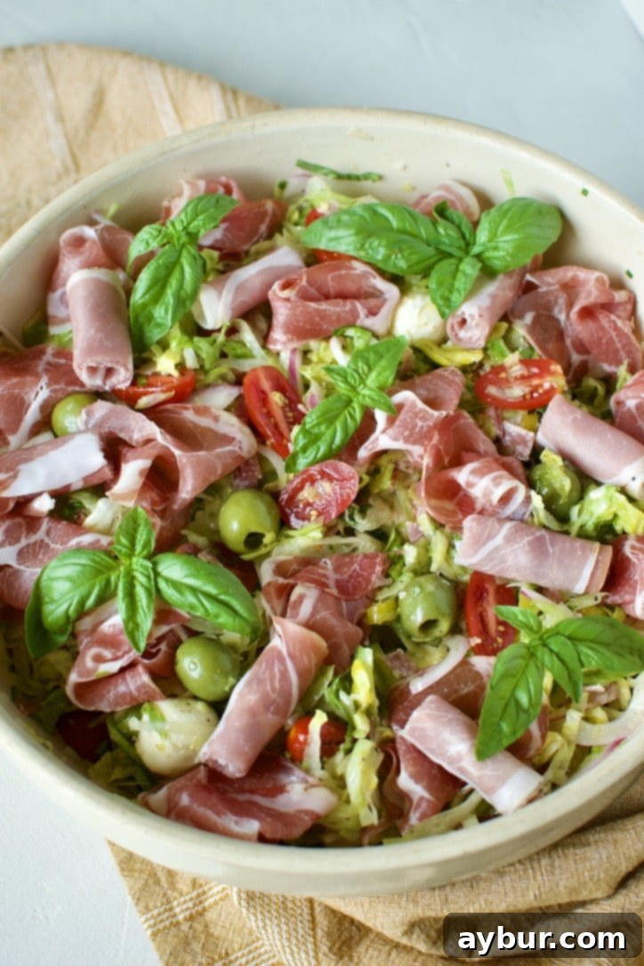 Mixed Italian Chopped Salad in a large bowl topped with prosciutto and basil leaves.