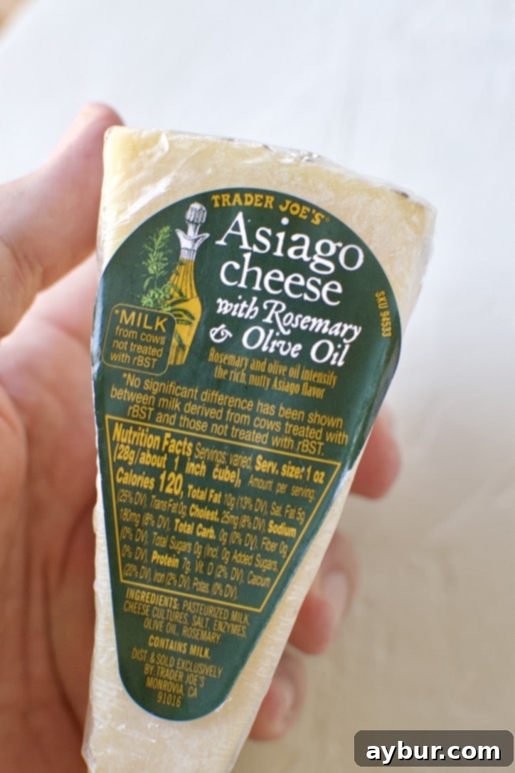 Velvety Creamy Polenta 4 A block of Rosemary Asiago cheese, partially grated, on a wooden cutting board.