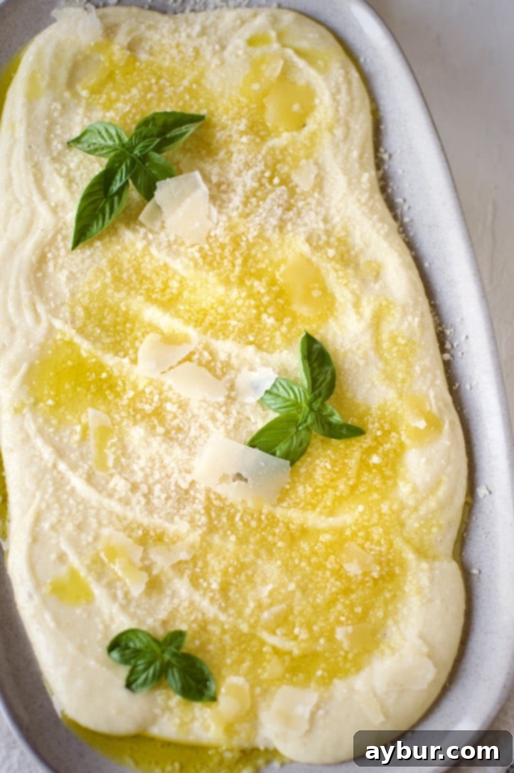 Velvety Creamy Polenta 5 Garlic cloves infusing in a saucepan with cream and chicken stock for creamy polenta.