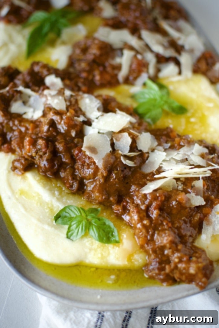 Velvety Creamy Polenta 6 Creamy polenta being served on a platter, drizzled with olive oil and sprinkled with parmesan cheese.