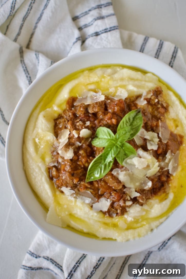 Velvety Creamy Polenta 8 Short Rib Bolognese served over Creamy Polenta and topped with shaved parmesan and fresh basil, ready to eat.
