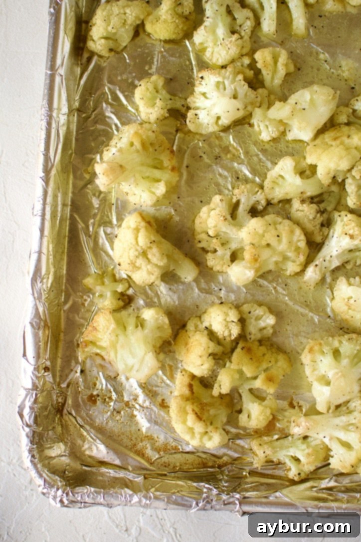 Roasted cauliflower florets showing slight browning on a baking sheet.