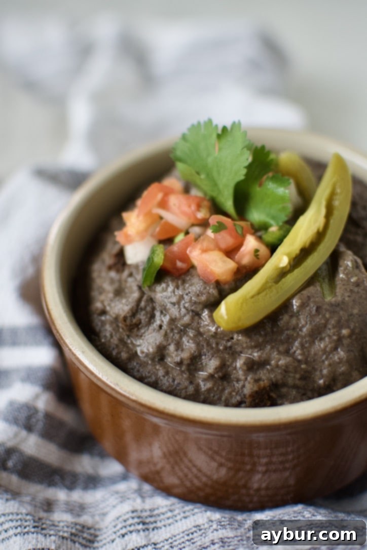 Easy Creamy Black Bean Dip 2 Black Bean Dip in a bowl, topped with pico de gallo, cilantro, and a slice of jalapeno.