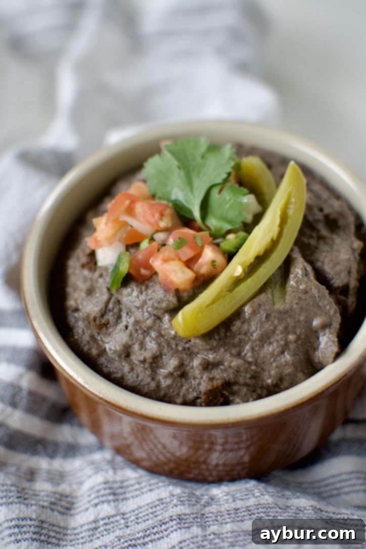 Easy Creamy Black Bean Dip 7 Black Bean Dip in a bowl, topped with pico de gallo, cilantro, and a slice of jalapeno.