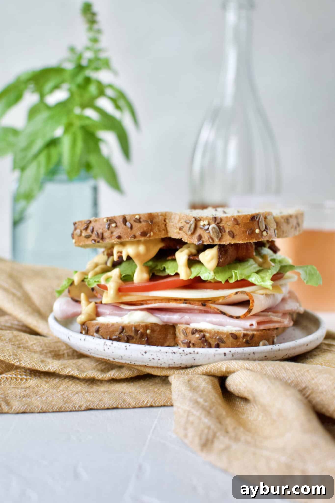 The final step in assembling the Club Sandwich: placing the second slice of bread on top, completing the stack.