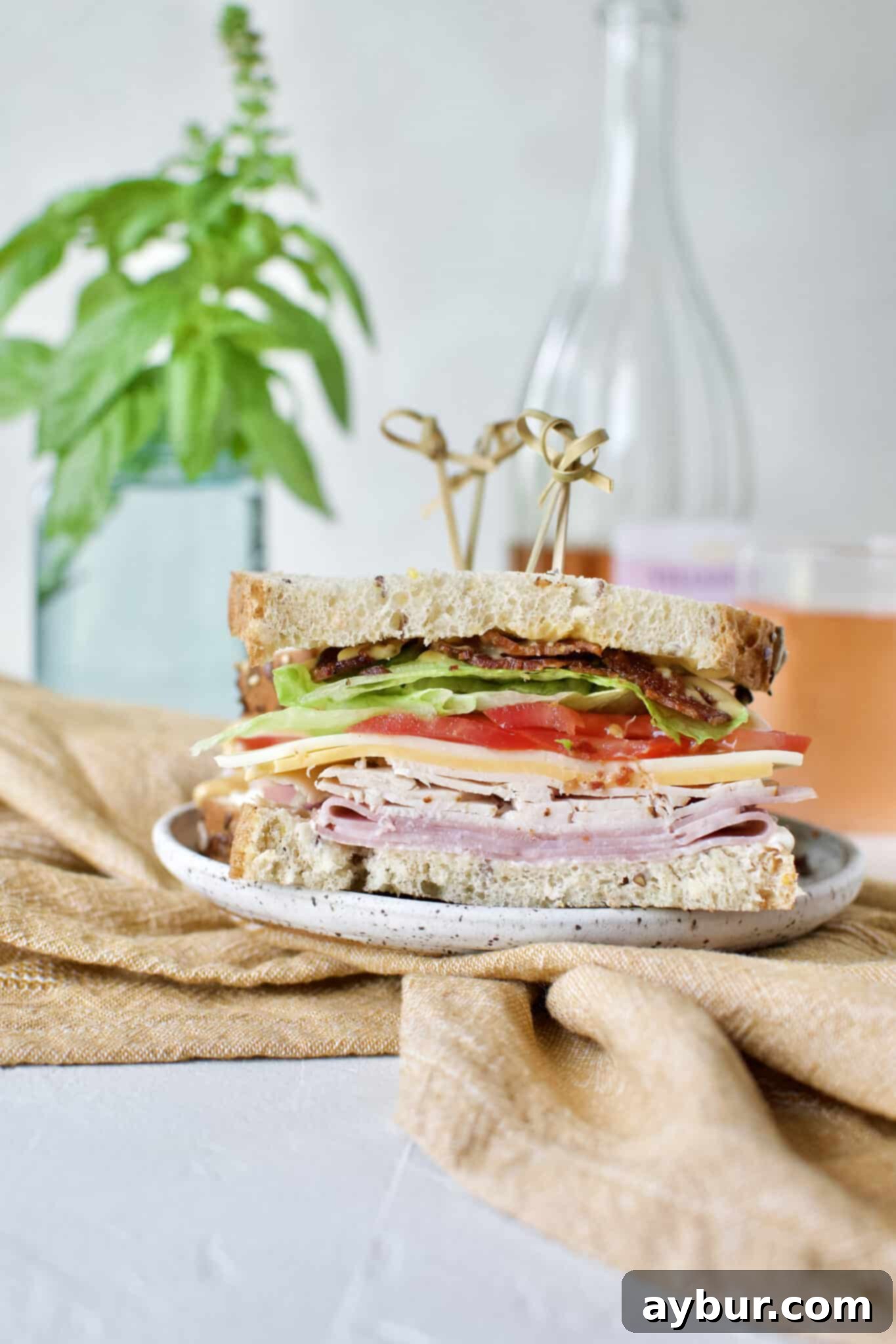The finished Club Sandwich, impeccably sliced in half and secured with picks, showcasing its beautiful layers and ready to be enjoyed.