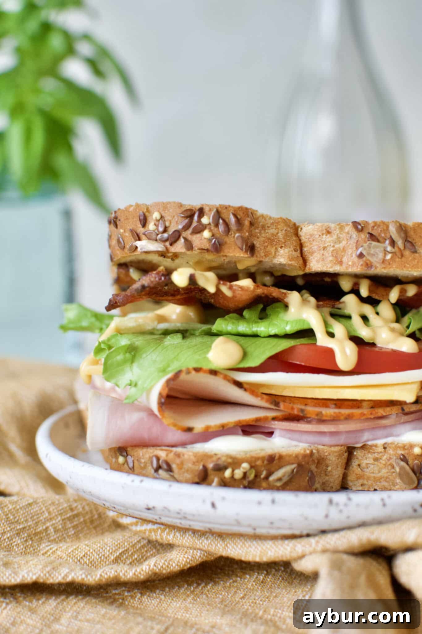 A beautifully presented Club Sandwich recipe on a plate, elegantly accompanied by a glass of refreshing rosé wine in the background.