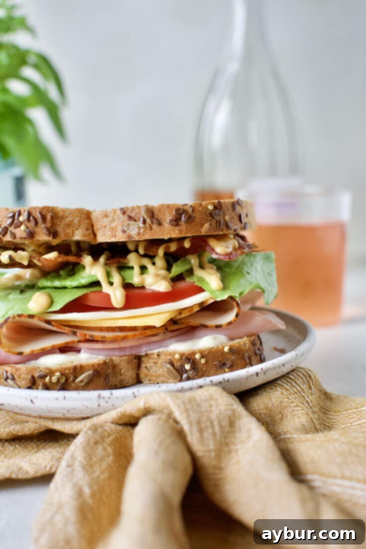 A delectable Club Sandwich on a plate, presented with a refreshing glass of rosé, inviting you to savor its layers.
