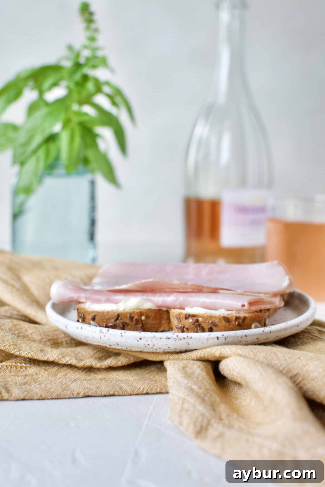 First slice of bread with mayonnaise, now topped with savory deli ham slices for the initial protein layer.